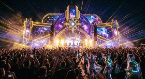 Large crowd at Celestial Sounds music festival facing a space-themed stage with lasers and pyrotechnics